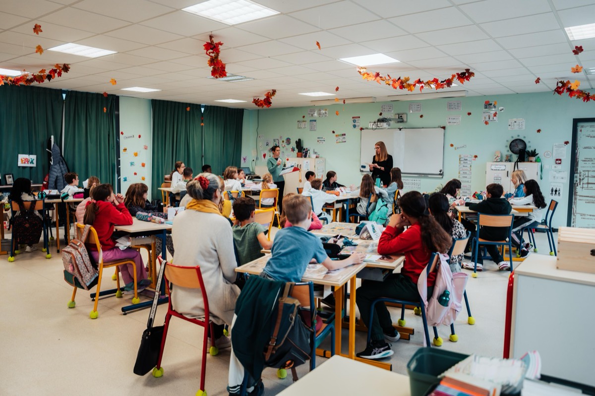 Une enseignante présentant le kit APQ 30 Gam'in à sa classe de CM1, les élèves assis et attentifs